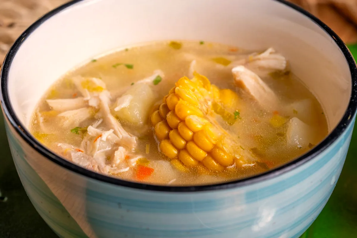 Low-carb chicken and corn soup with shredded chicken, zucchini and fresh herbs